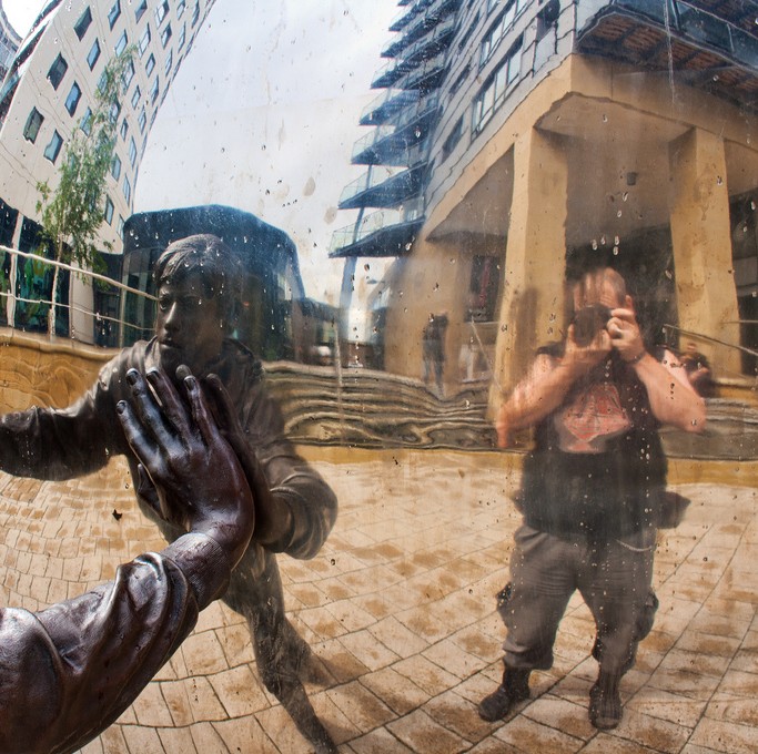 Image of a reflection of a photographer in a silver sphere shaped sculptue