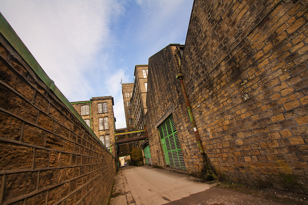 Tilted aspect, a road between two gritstone mill buildings