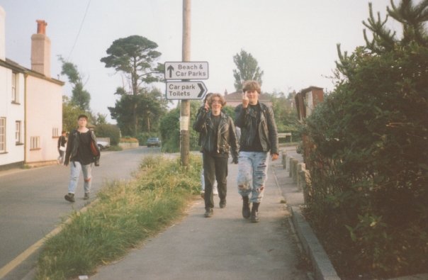 Three teenagers in alternative clothing walking down the street in a village