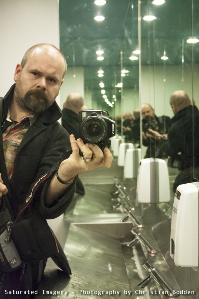 A man holding a camera in a bathroom reflected multiple times in mirrors