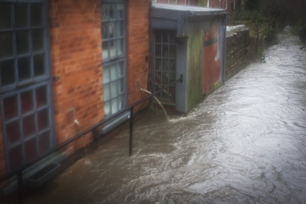 Beck in spate close to flooding in through windows of a house
