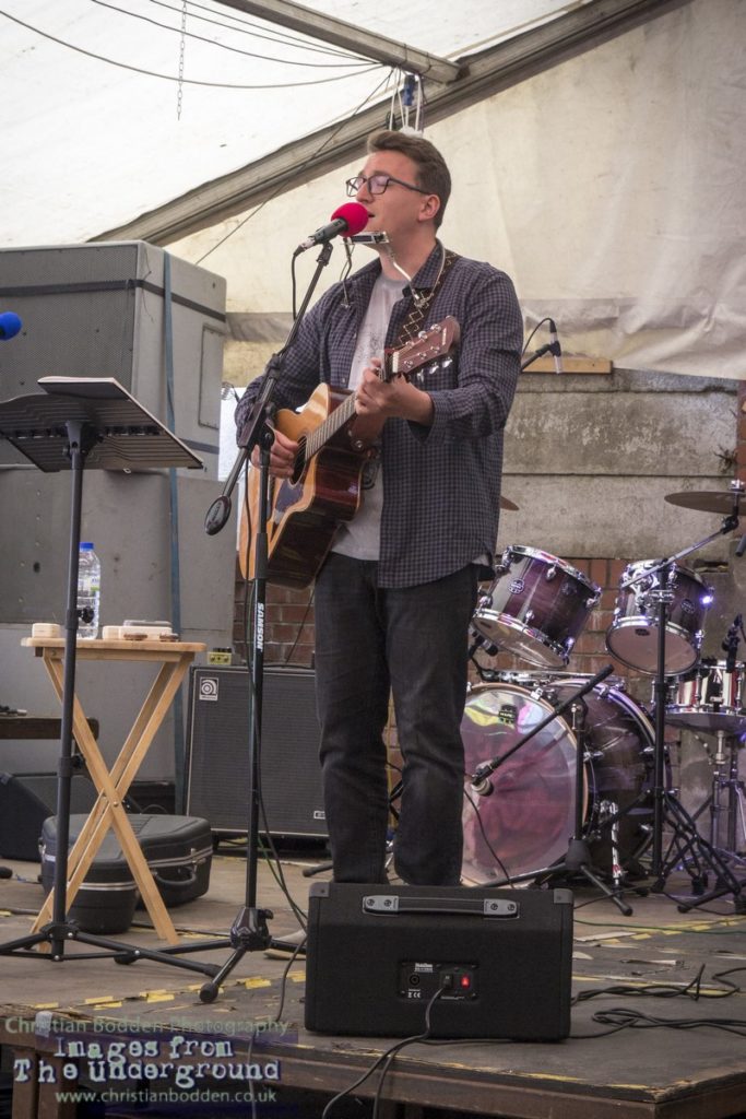 A man playing guitar on stage in a marquee