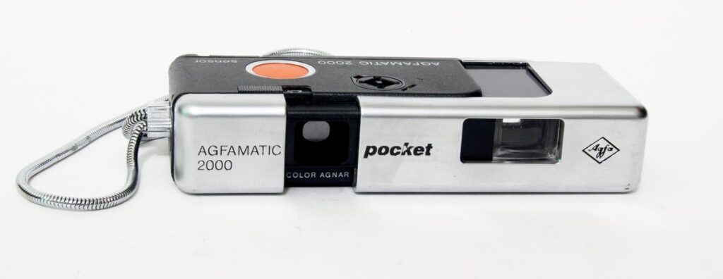 A 100 film camera. Text on body reads Agfamatic 2000 Pocket.