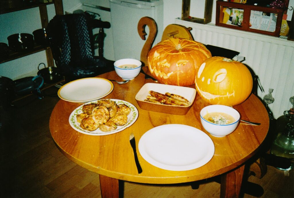 A table with pumpkin soup and sausages. 